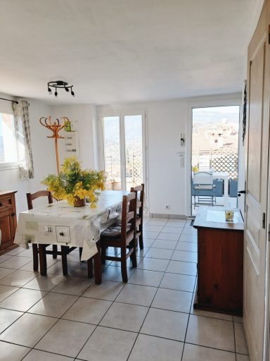 Salle à manger lumineuse avec table, chaises et accès à un balcon.