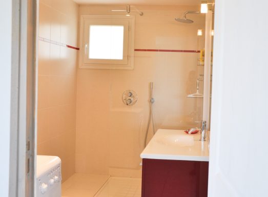 Salle de bains moderne avec douche, lavabo et sol clair.