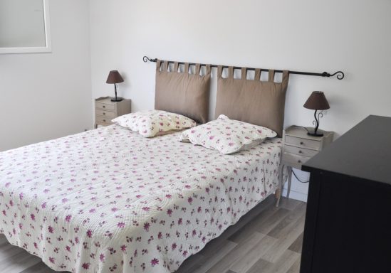 Chambre lumineuse avec lit double, draps à fleurs et lampes de chevet.